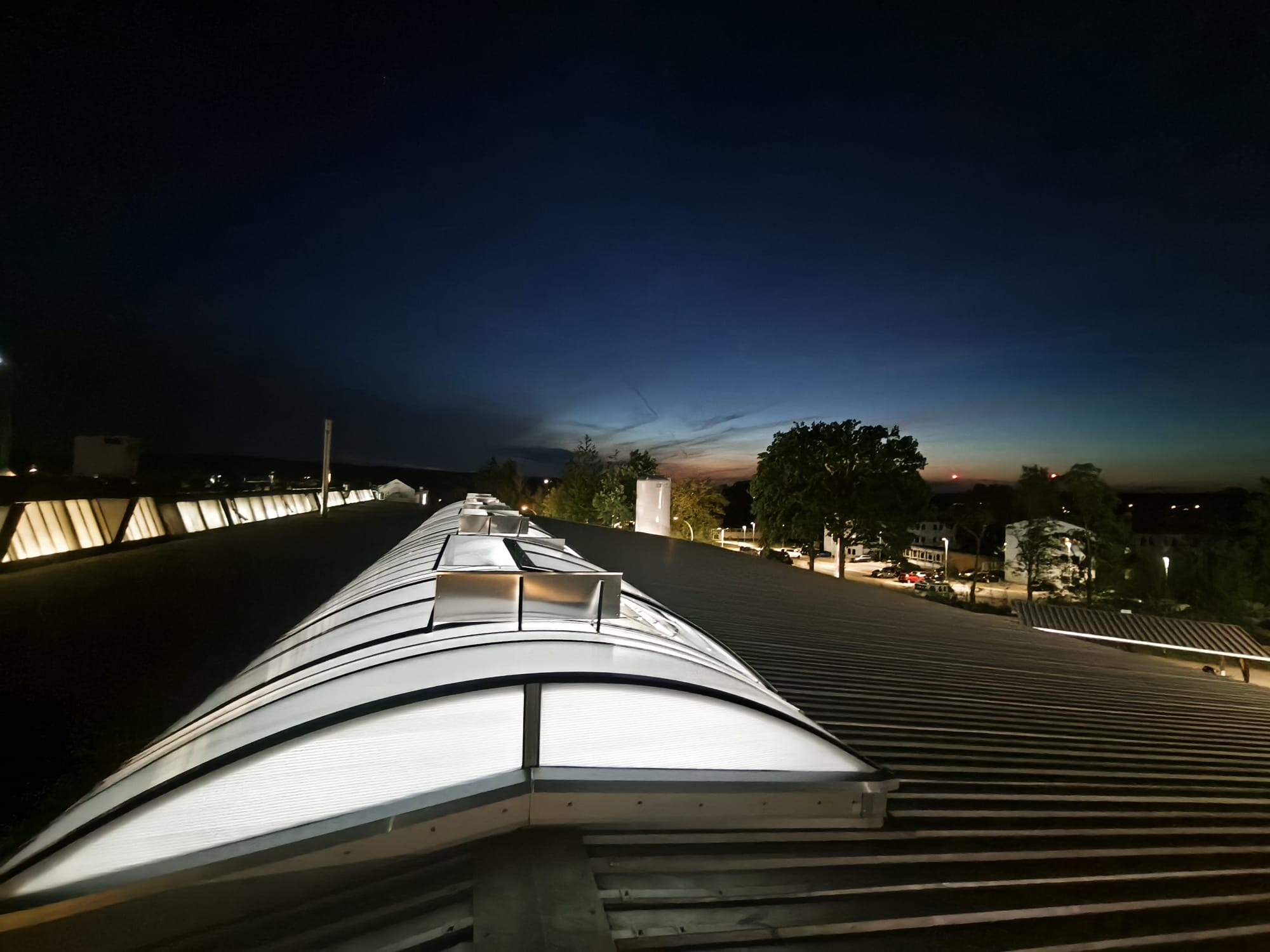 Industriedach mit Lichtkuppeln und geöffneten Rauchabzugsgeräten bei Nacht